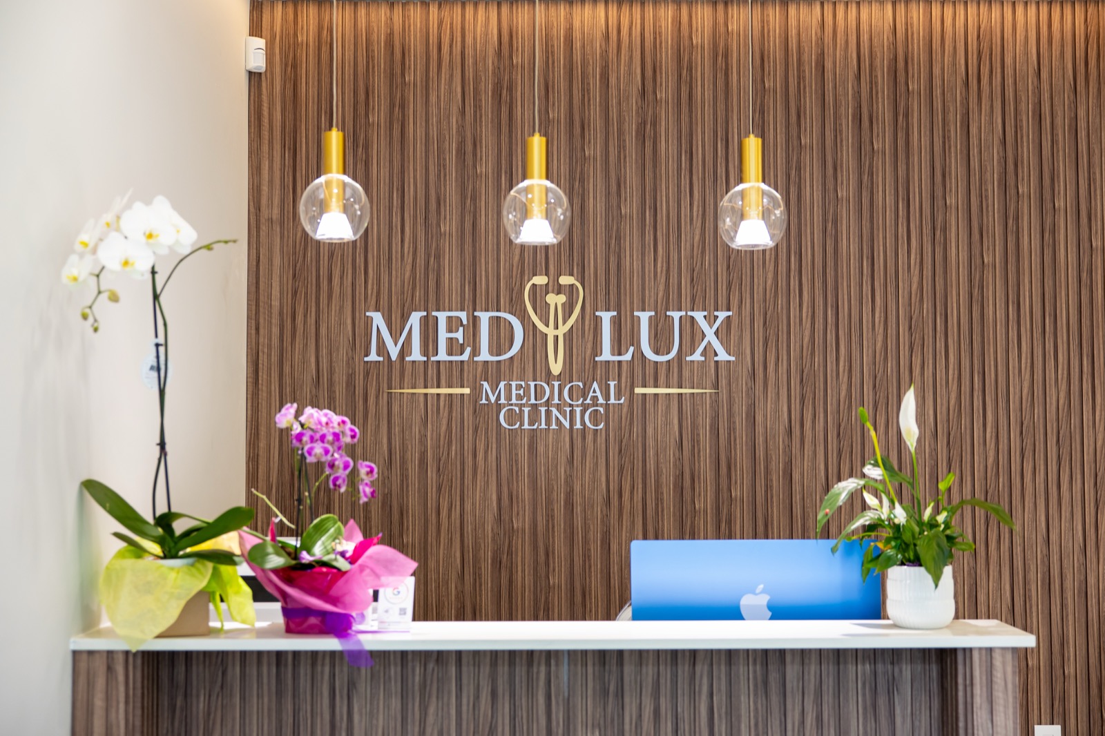MedLux Medical Clinic reception with signature walnut wall and orchids